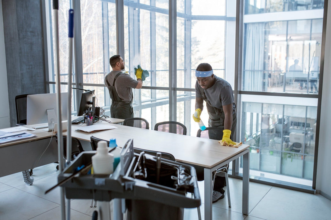 Commercial cleaning service workers wiping office table and cleaning window to ensure a spotless and professional workspace.
