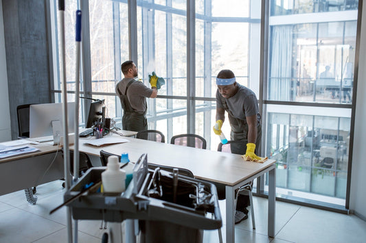 Commercial cleaning service workers wiping office table and cleaning window to ensure a spotless and professional workspace.